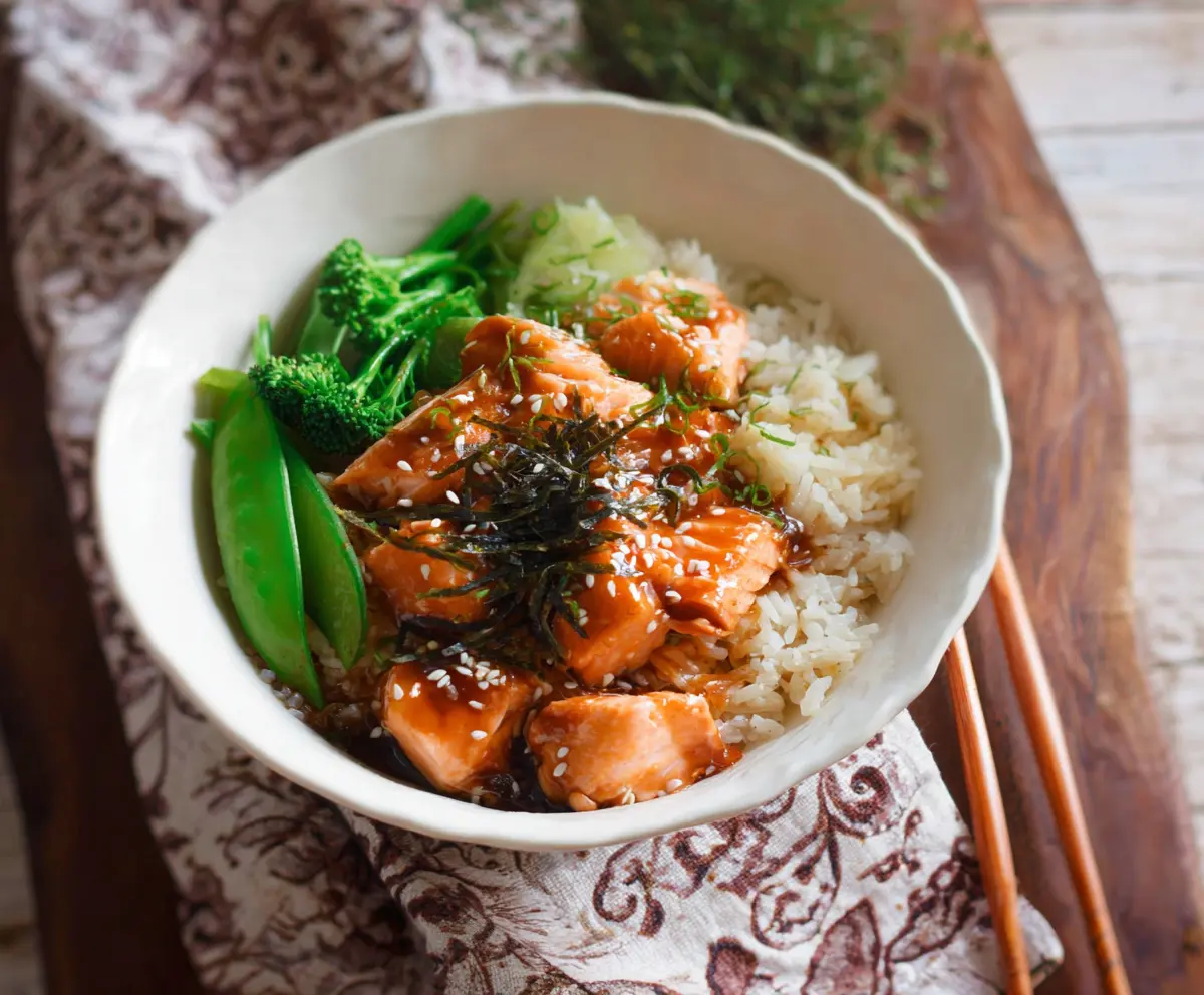 Delicious teriyaki salmon served over rice in a vibrant bowl with vegetables.
